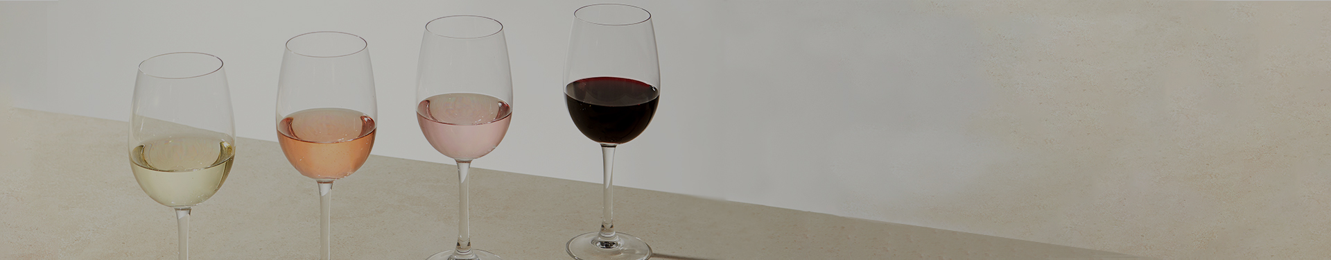 4 wine glasses lined up, filled with red wine, white wine, rose wine and moscato wine
