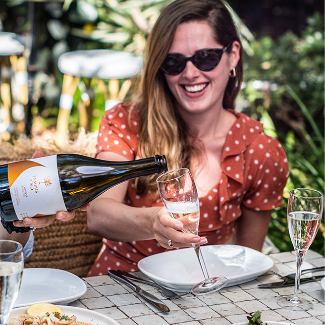 Girl in red polka dot dress smiling whilst receiving a glass of Tempus Two Lighten Up Prosecco